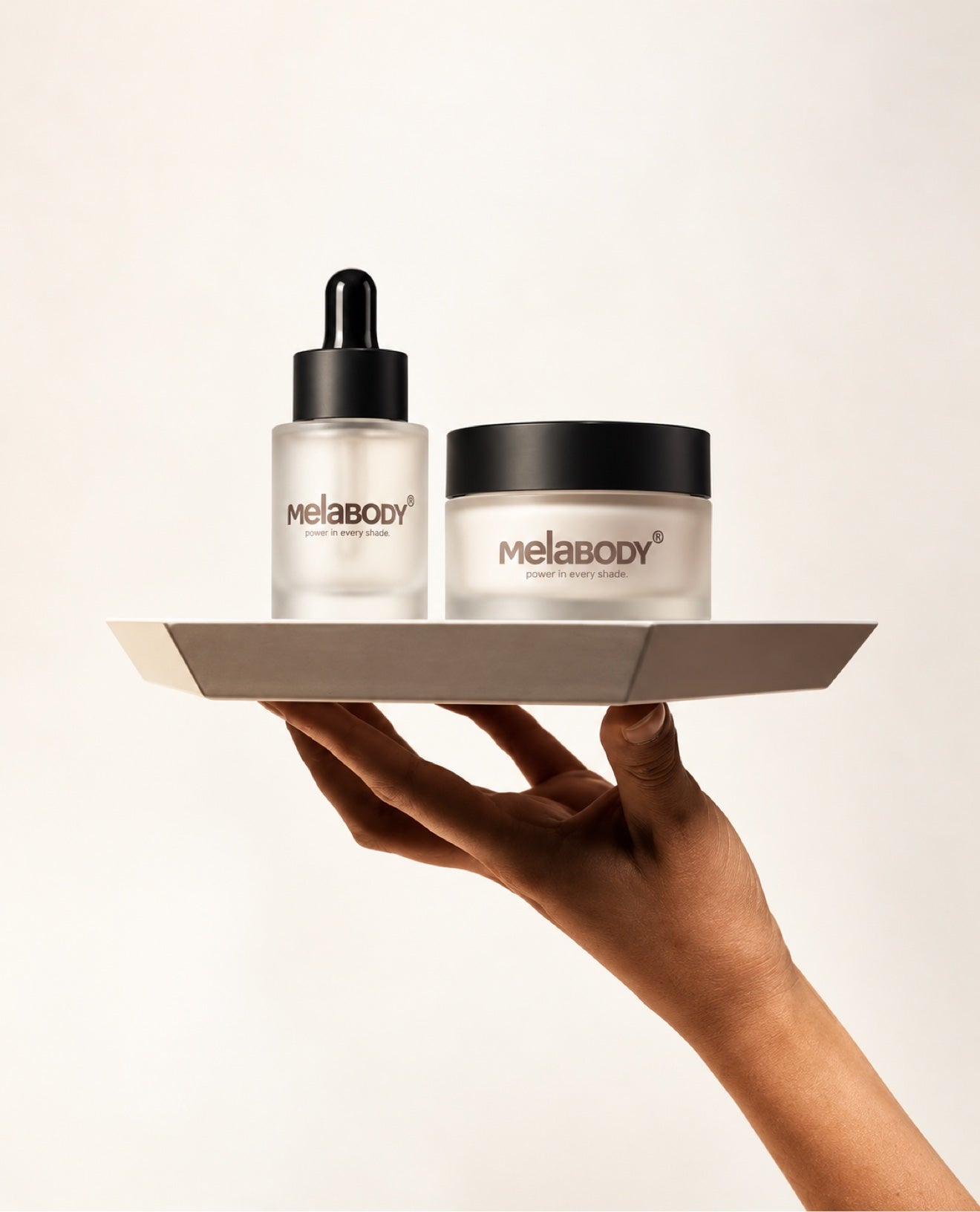 MelaBODY serum and cream presented on a tray, held up by a hand