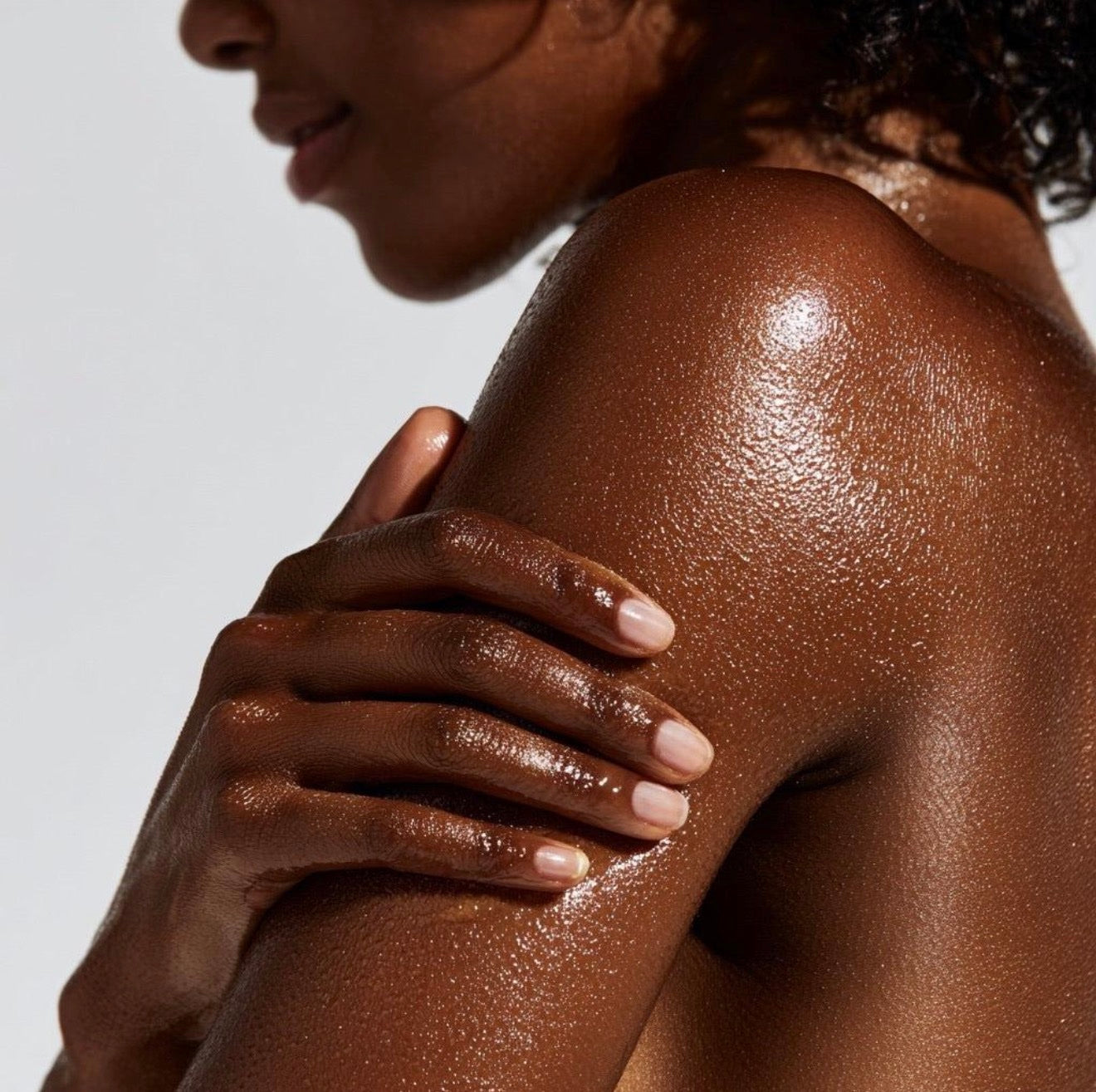 Woman's glowing shoulder and back, hand resting on her arm
